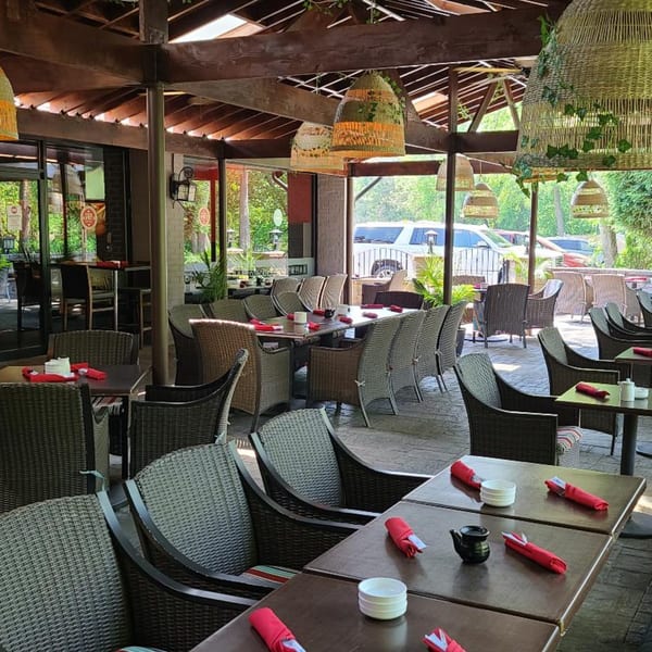 Spacious outdoor dining area at Sogo Hibachi and Sushi Lounge with wicker chairs and tables set with red napkins.