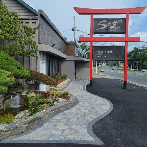 Exterior of Sogo Hibachi and Sushi Lounge with a red torii gate sign and landscaped entrance.