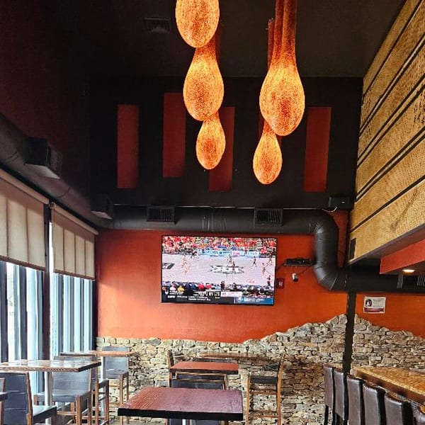 Interior of Sogo Hibachi and Sushi Lounge with modern lighting, a TV, and stone wall accents.