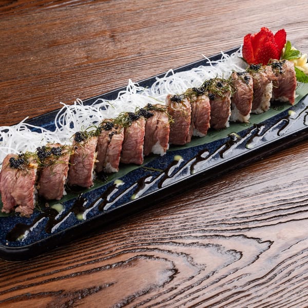 Sogo Hibachi and Sushi Lounge's beef sushi roll with caviar, seaweed, and shredded daikon on a blue plate.