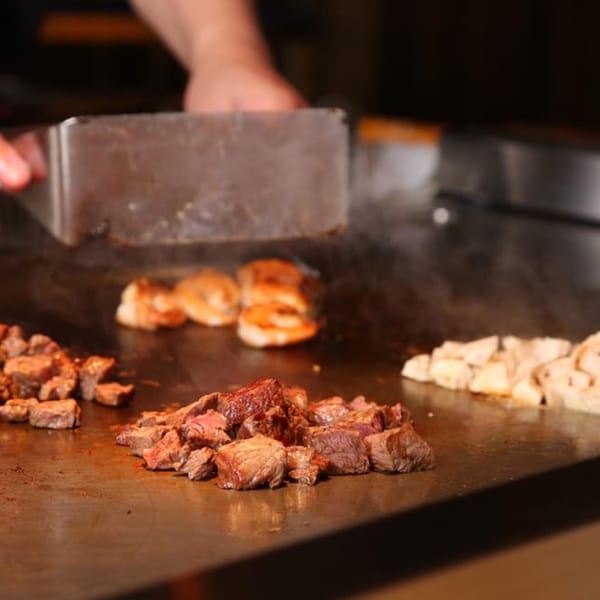 A chef cooking steak, shrimp, and chicken on a hibachi grill at Sogo Hibachi and Sushi Lounge.