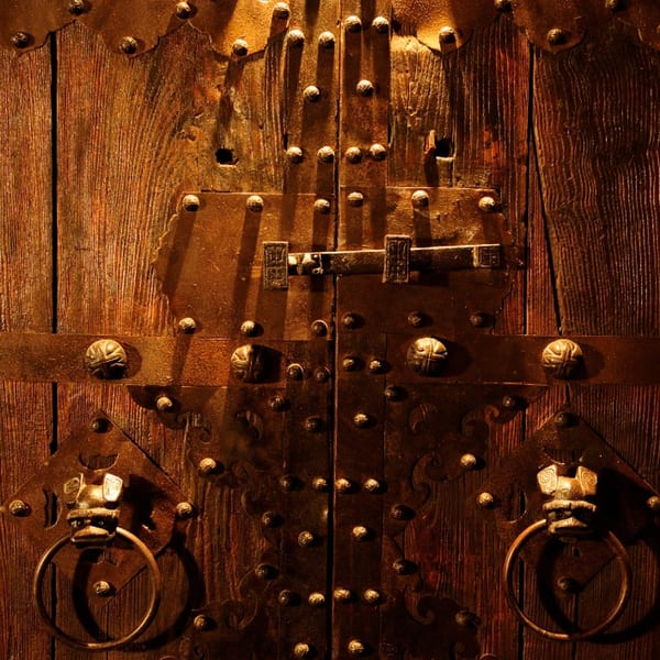 Close-up of a dark wooden door with ornate metal hardware and a decorative door knocker.
