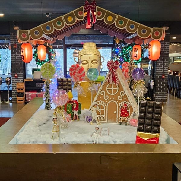 A festive Japanese-themed Christmas display with a Buddha head, gingerbread house, and lanterns.