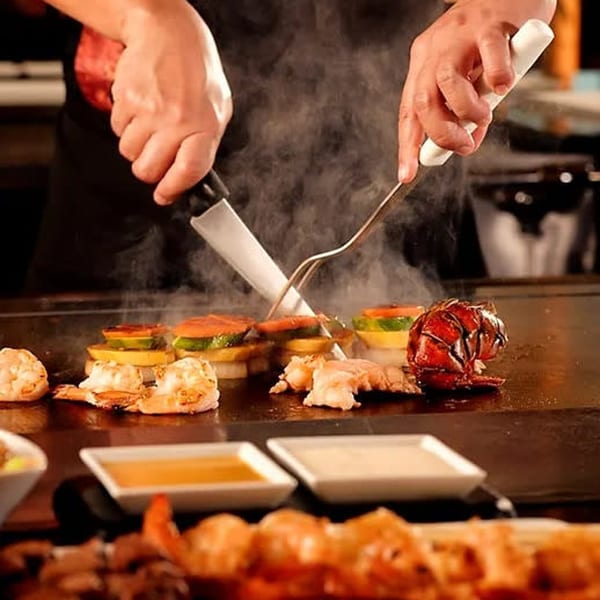 A chef cooks shrimp, lobster, and vegetables on a steaming hibachi grill at Sogo Hibachi.