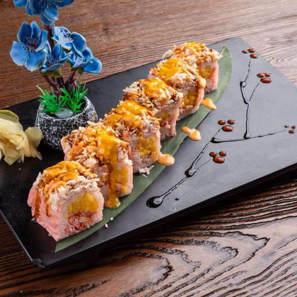 Sogo Hibachi and Sushi Lounge's sushi rolls with orange sauce, ginger, and a blue floral decoration.