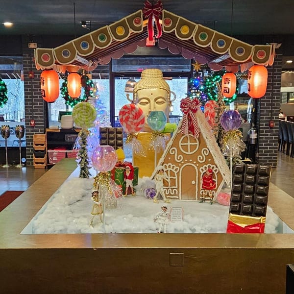 A festive holiday display at Sogo Hibachi with a gingerbread house, Buddha statue, and Japanese lanterns.